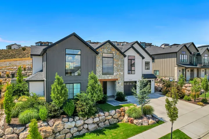 Modern architectural style featuring large picture windows, stone and vertical siding accents, an attached two-car garage, and a concrete driveway