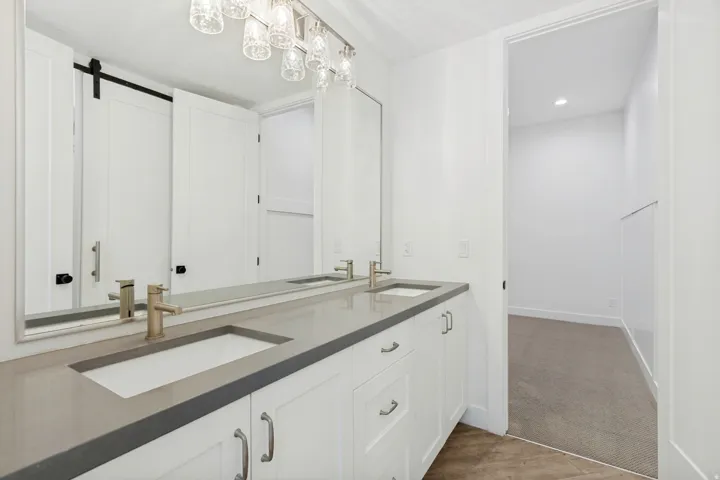 Dual vanity with integrated rectangular sinks, expansive counter space, white shaker cabinetry, and brushed nickel hardware