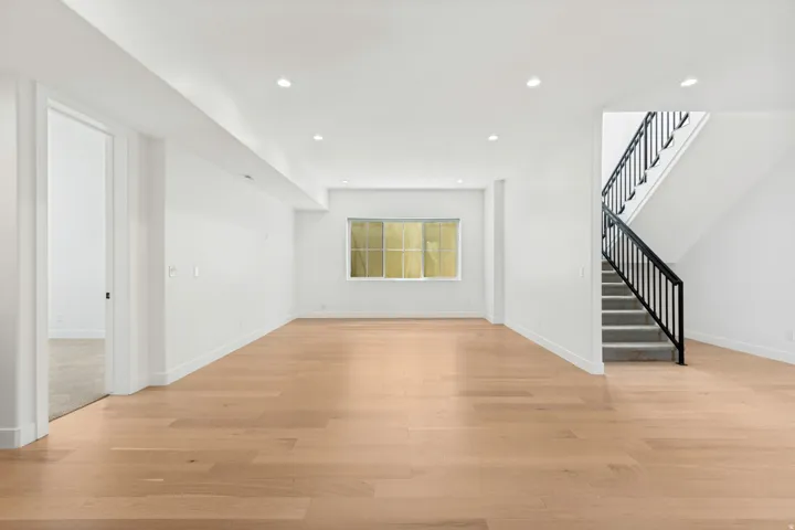 Recessed lighting, wood-finish flooring, staircase with metal balusters, and a window providing natural illumination