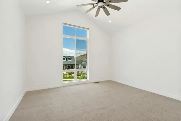 Vaulted ceiling with a ceiling fan, large multi-pane window, recessed lighting, and carpeted flooring