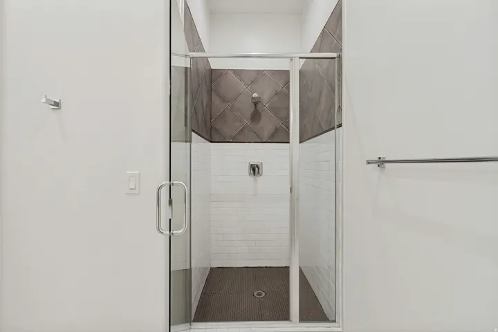 Glass-enclosed shower with subway tile, textured accent tile, and a dark-toned shower pan