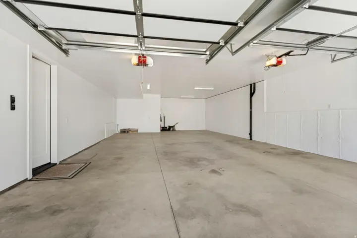 Spacious garage with concrete flooring, automatic garage door openers, and a side entry door