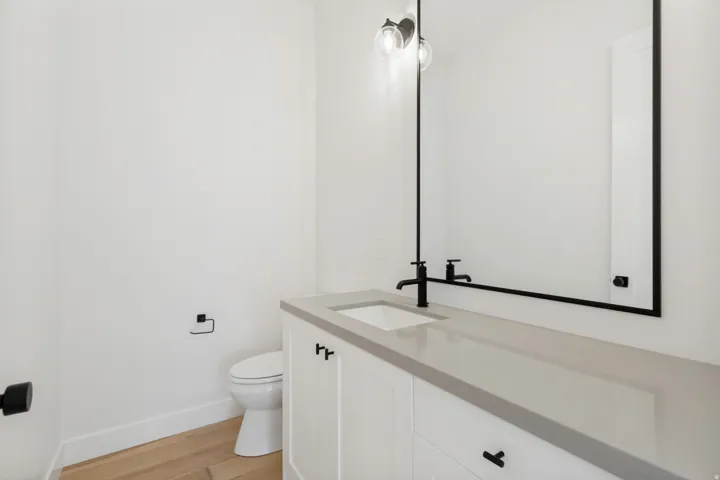 White vanity with a light-toned countertop, undermount sink, and matte black faucet