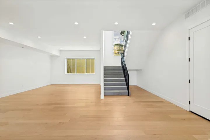 Spacious room with wood-finish flooring, recessed lighting, and a window