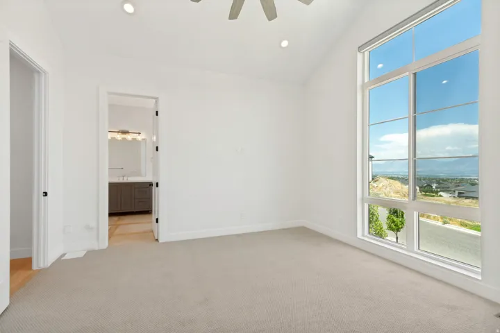 Expansive window wall with mountain scenery, vaulted ceiling, recessed lighting, ceiling fan, and carpet flooring
