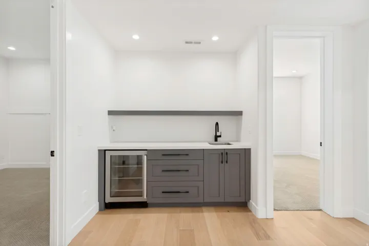 Wet bar featuring gray cabinetry, a beverage refrigerator, white countertop, and a matte black faucet