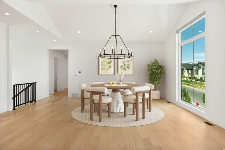 Vaulted ceiling with recessed lighting, expansive picture window, light wood-finish flooring, and a black wrought iron chandelier