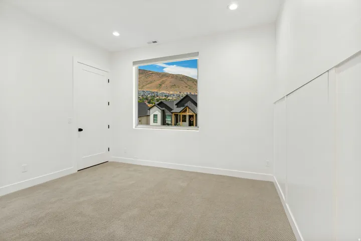 Recessed lighting, wall paneling, light-toned carpeting, white trim, and a window with a mountain backdrop