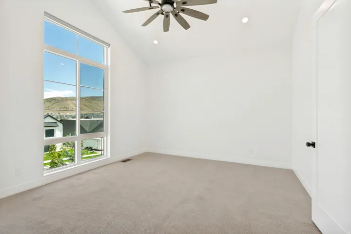 Vaulted ceiling with integrated lighting, a ceiling fan, and large picture windows