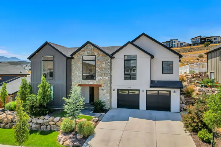 Contemporary exterior with mixed material facade, stone accents, two-car garage, and established landscaping
