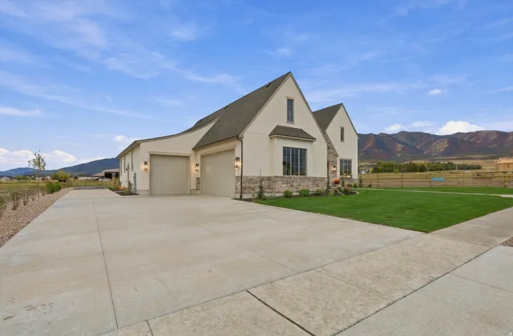 Stucco exterior with stone accents, steeply pitched rooflines, and a two-car garage