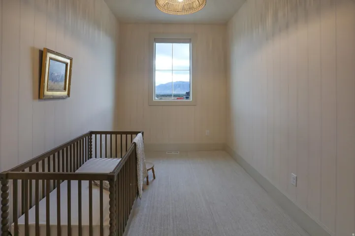 Recessed single window with exterior scenery, wall paneling, light carpet flooring, and a woven pendant light fixture
