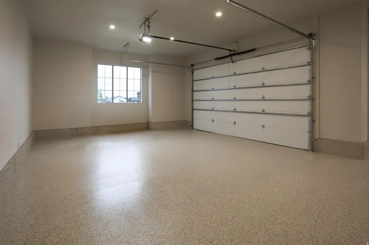 Spacious garage featuring a durable epoxy floor finish, a multi-pane window, flush mount lighting, and an overhead garage door with opener