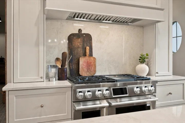 Stainless steel range with a double oven, stone-finish backsplash, and matching stone countertops