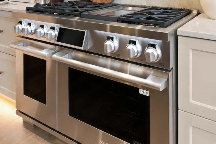 Stainless steel professional-grade range with multiple burners, griddle, and double ovens