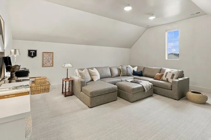 Recessed ceiling lighting, sloped ceiling detail, and a window with exterior views
