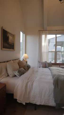 Vaulted ceiling, exposed wood beam, large window, wood-finish flooring, and built-in window seating