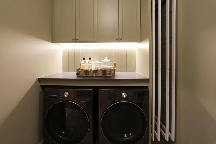 Built-in cabinetry with under-cabinet lighting, dark countertop, and integrated washer and dryer units