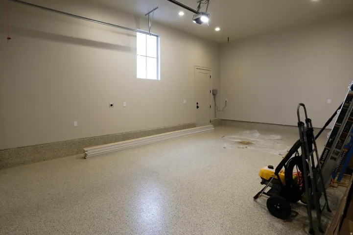 Spacious garage featuring a durable epoxy-coated floor, high ceilings, a single window, recessed lighting, and a solid entry door