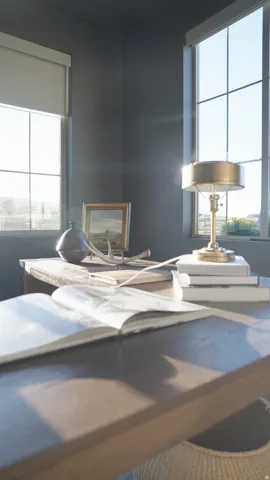 Two large windows with roller shades, dark wall paint, and a wooden desk
