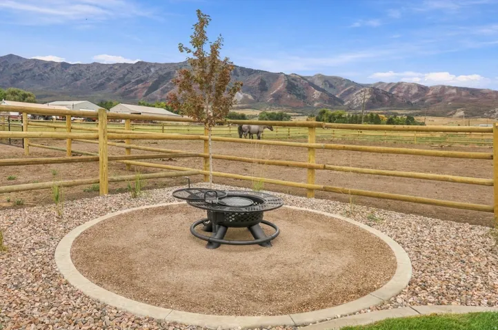 Circular fire pit area with an aggregate base, bordered by decorative gravel and a young tree