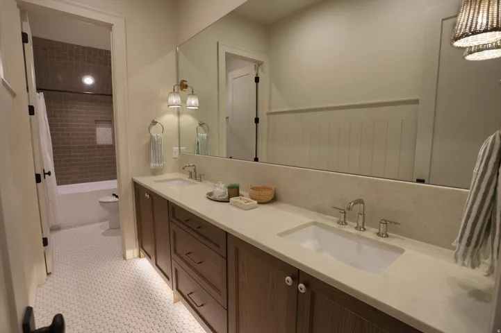 Dual vanity with integrated sinks, a continuous mirror, and a wood-finish cabinet