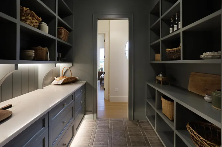 Built-in cabinetry with ample shelving, spacious countertop, under-cabinet lighting, and textured floor tile