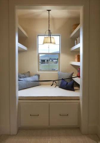 Window nook with built-in storage drawers, integrated shelving, and a decorative pendant light fixture