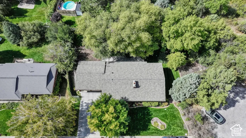 Asphalt shingle roofing, mature trees, landscaped front yard with green lawn, paved driveway