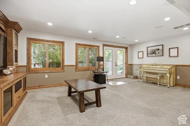 Wall-mounted cabinetry, wood-framed windows with plantation shutters, recessed lighting, double French doors, and carpet flooring