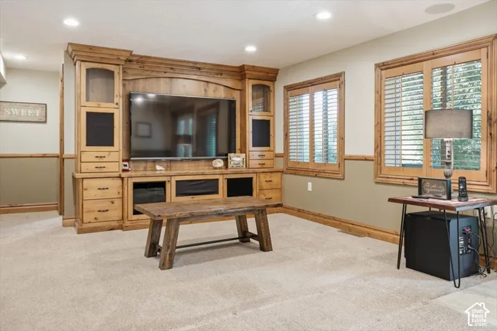 Integrated custom wood entertainment center with display cabinetry, recessed lighting, and wall-mounted television