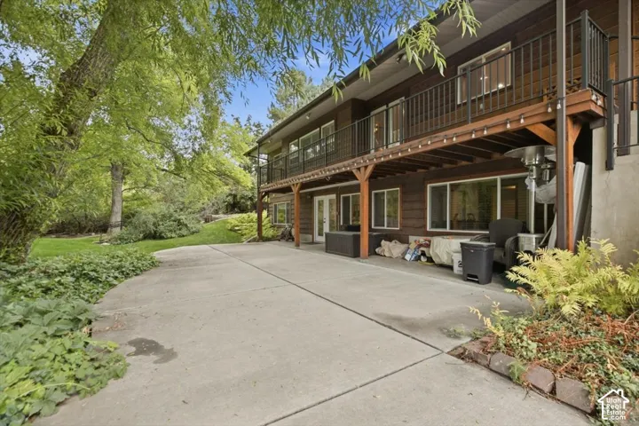 Expansive concrete patio with direct access to lower level, complimented by a second-story wooden deck featuring a black metal railing