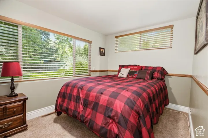 Wall-to-wall carpeting, large picture window with blinds, wood trim, and two-tone wall paint