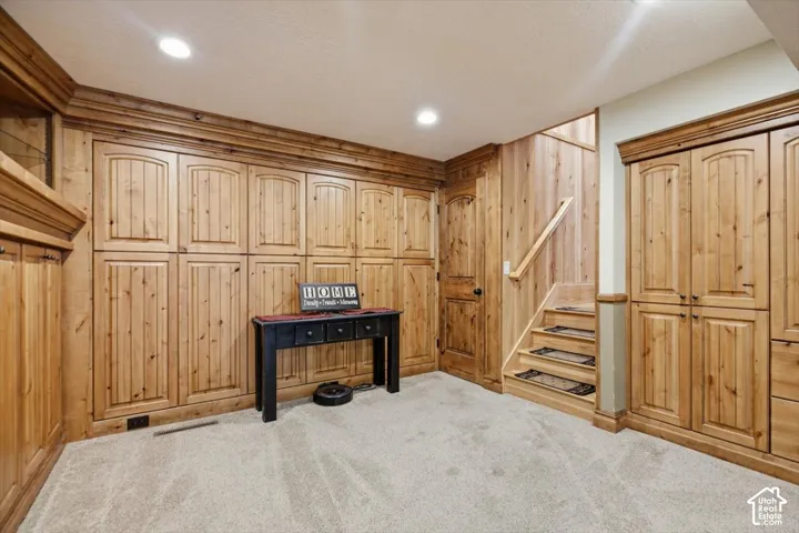 Extensive wood-finish cabinetry, paneled walls, staircase with a wood handrail, and recessed ceiling lighting