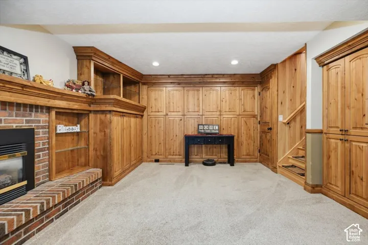 Built-in wood cabinetry, brick fireplace, wood paneling, and carpet flooring
