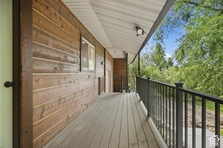 Deck with composite flooring, black metal railings, and a wood-paneled exterior