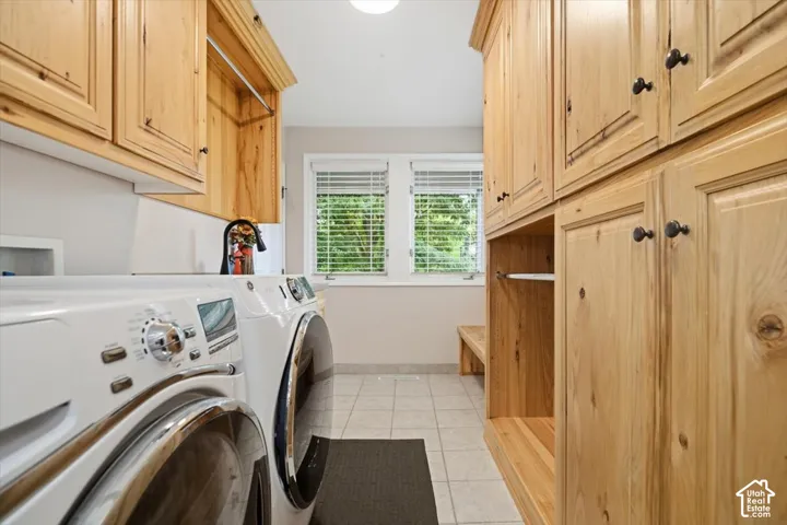 Laundry area featuring extensive wood-finish cabinetry, tiled flooring, and a built-in bench
