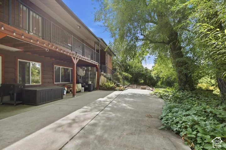 Multi-level exterior with a second-story balcony featuring black railings and wood-finish siding