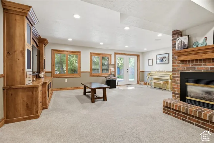 Spacious room featuring a built-in media center, brick fireplace with a wood mantle, carpet flooring, and recessed lighting