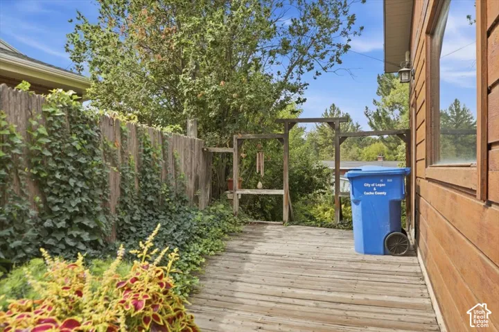 Exterior wood siding, wooden deck, wooden privacy fence, mature trees, and established landscaping