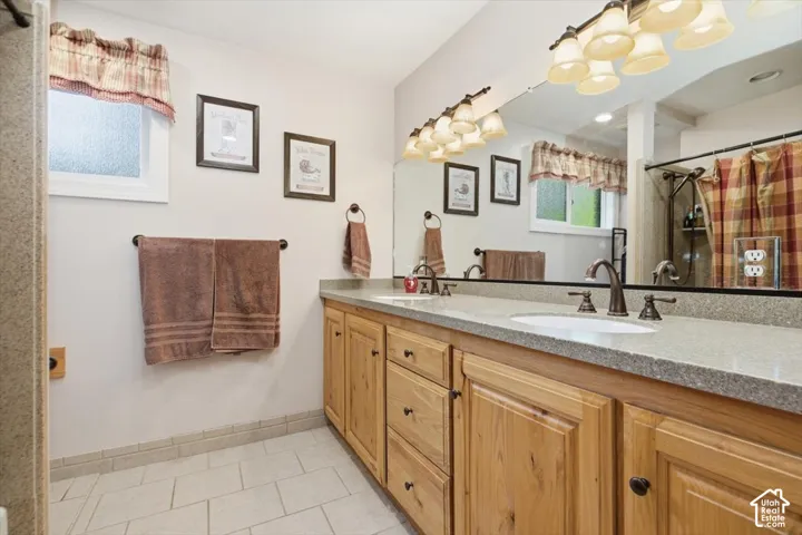 Dual basin vanity with wood cabinetry and stone-finish countertop, under-mount sinks, and oil-rubbed bronze fixtures
