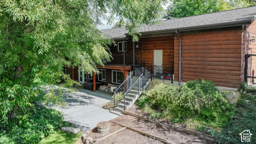 Exterior featuring wood-sided construction, a multi-level deck with black railings, and a concrete patio