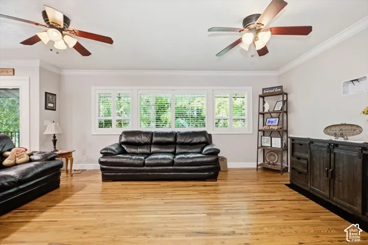 Hardwood flooring throughout, multiple windows with blinds, ceiling fans, crown molding, and a built-in media console