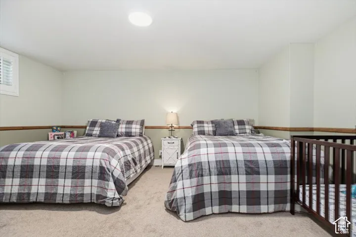 Recessed ceiling lighting, light wall paint, wood-finish chair rail, carpeted flooring, and window with plantation shutters