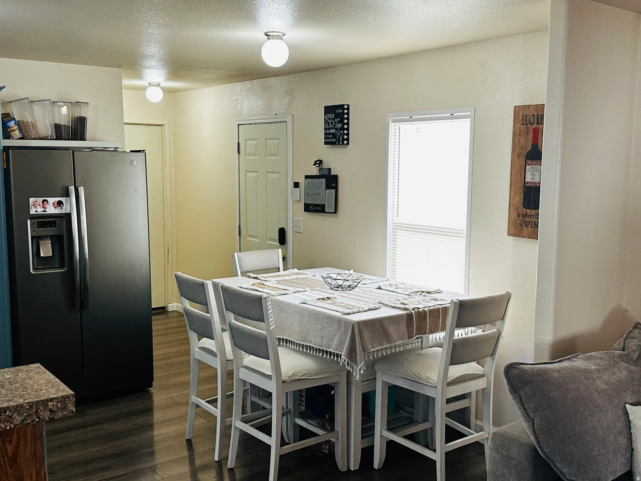 Kitchen area featuring a stainless steel refrigerator, wood-finish flooring, and a dining space with a window