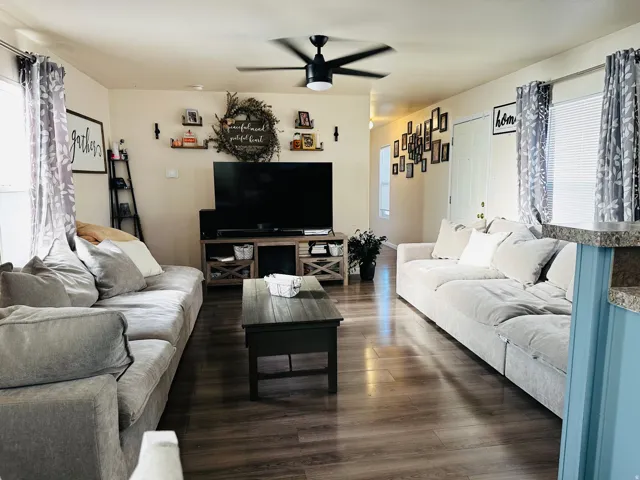 Wood-finish flooring throughout, ceiling fan, white paneled door, and recessed lighting
