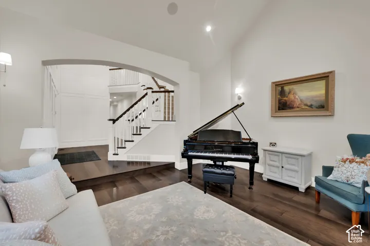 Hardwood-style flooring throughout, an arched doorway, and a white staircase with dark wood railing