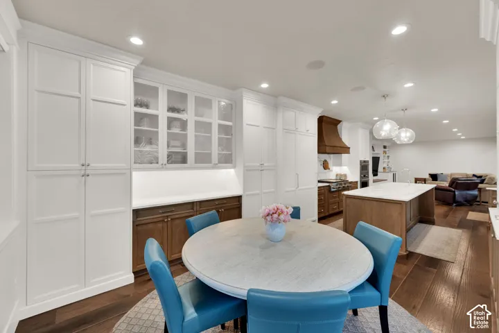 Built-in white cabinetry, glass-front upper cabinets, dark wood-finish lower cabinets, and recessed lighting