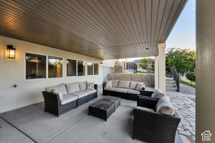 Covered patio with concrete flooring, wall-mounted exterior lighting, and multiple windows