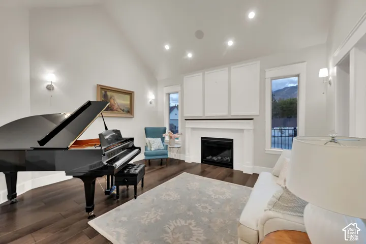 Vaulted ceiling, recessed lighting, wood-finish flooring, fireplace with white mantel, and multiple windows